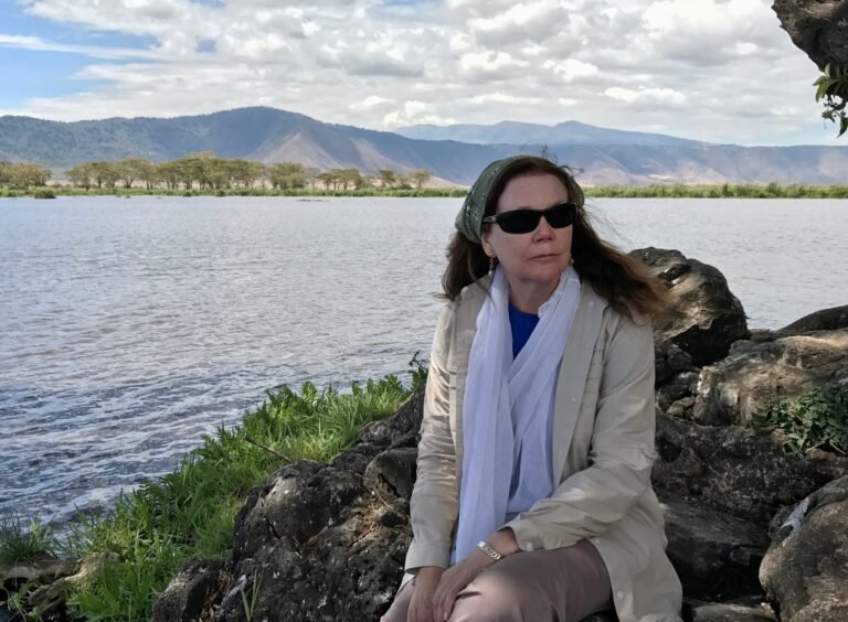 Benson Safaris | A woman staring off on deep thought at the edge of a lake in Ngorongoro crater