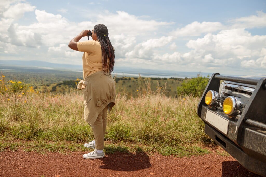 Benson Safaris | African American female guide using binoculars, looking for wildlife