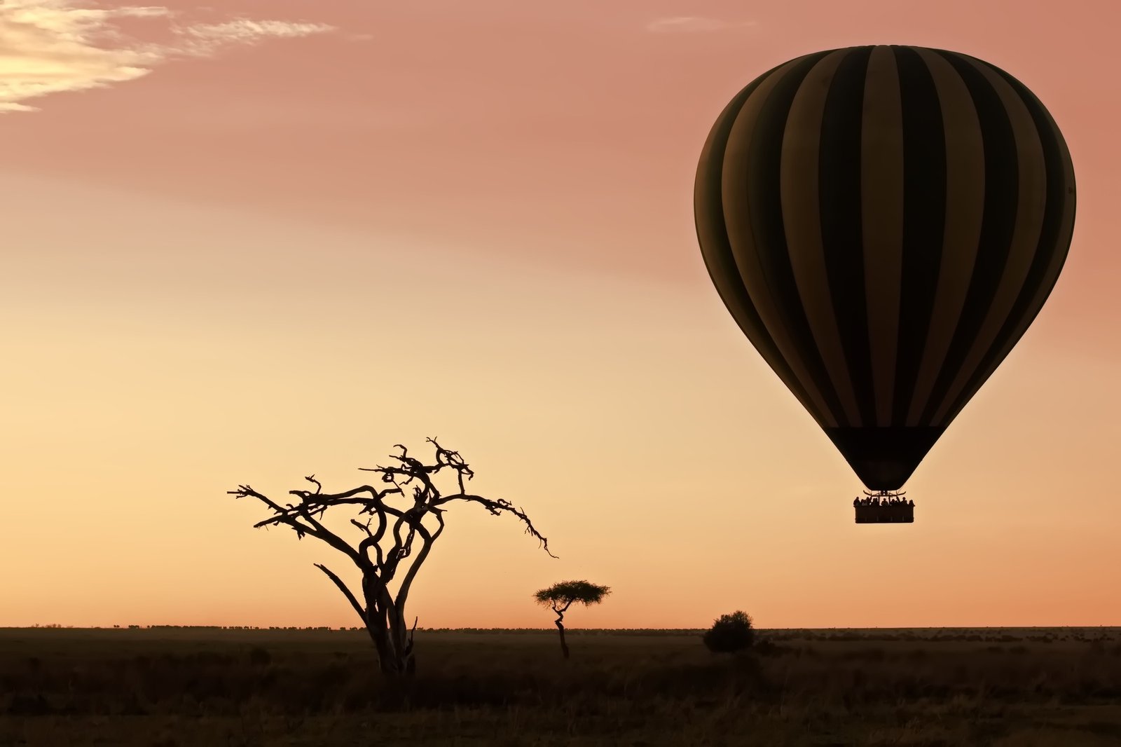 Benson Safaris | Air balloon flying over a barren landscape at sunset Serengeti, Tanzania