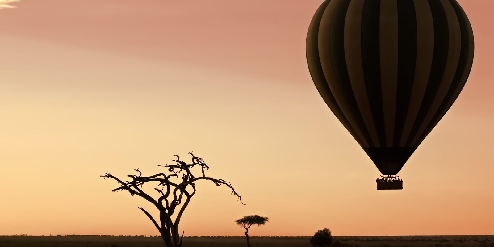 Benson Safaris | Air balloon flying over a barren landscape at sunset Serengeti, Tanzania
