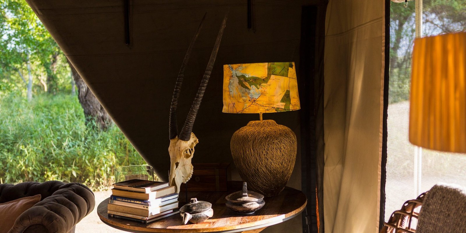 Benson Safaris | The interior of a tent in a safari camp, tent sides rolled up.