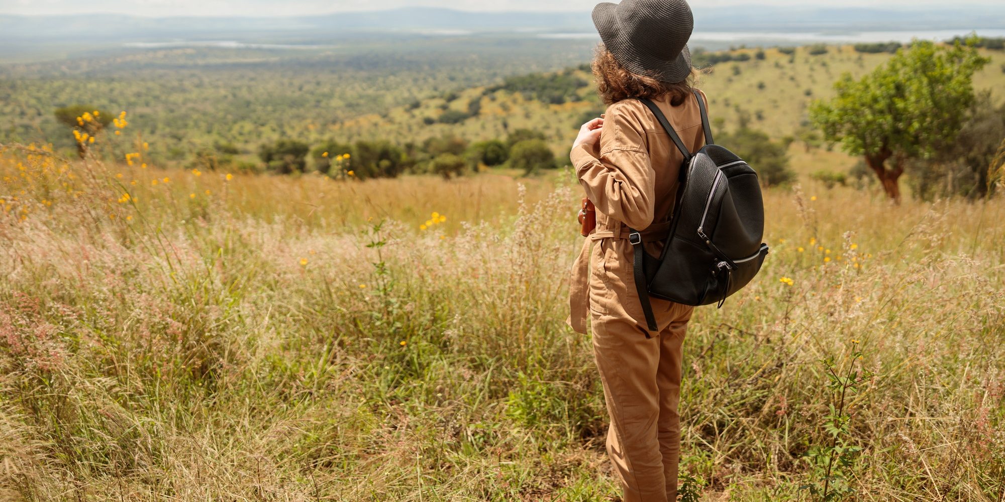 Benson Safaris | Young woman with backpack enjoying the views of the savannah